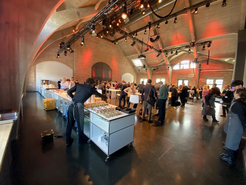 Catering-Stationen und Gäste beim Networking in einer historischen Backsteinhalle