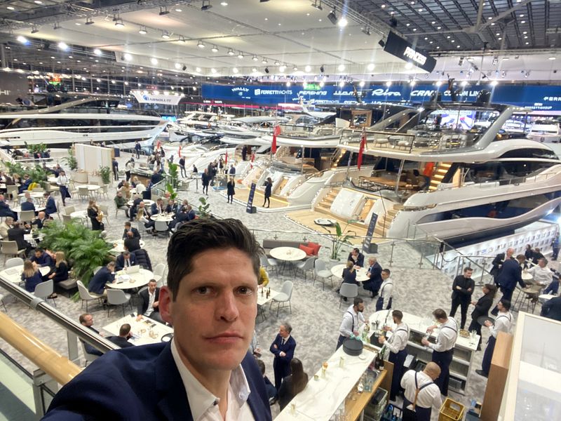 Lasse Dienes im Anzug in einer Messehalle der boot Düsseldorf, im Hintergrund Yachten, Stände und Besucher
